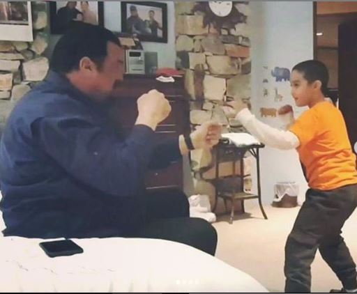A picture of Kunzang Seagal playing play-fight with his dad Steven Seagal.